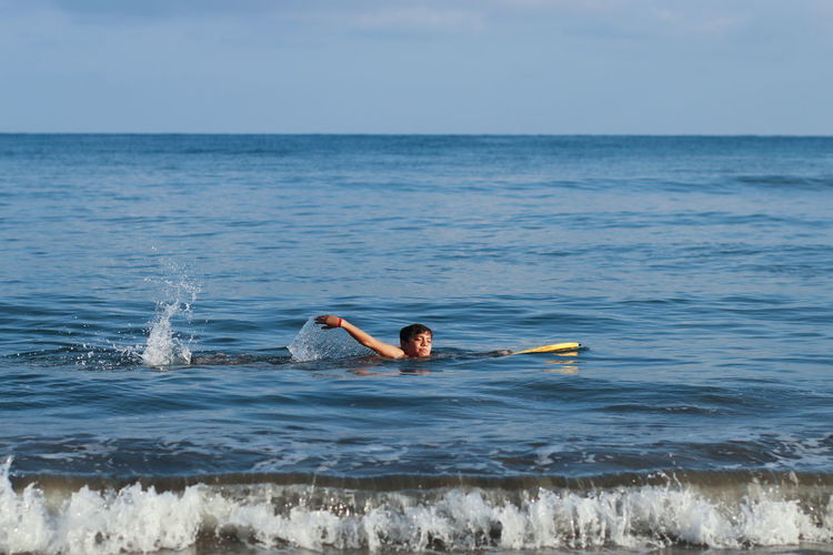 Man surfing in sea against sky