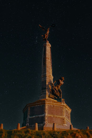 Low angle view of statue of historic building at night
