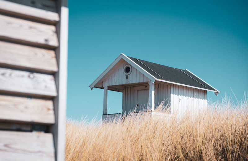 Wooden house on field against clear blue sky
