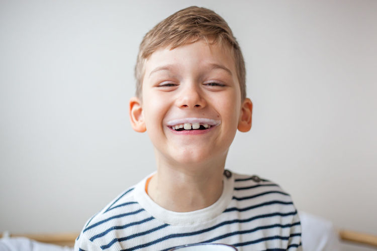 Portrait of smiling boy with milk mustache against wall
