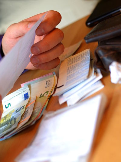 Cropped image of person reading bill by five euro banknotes on table
