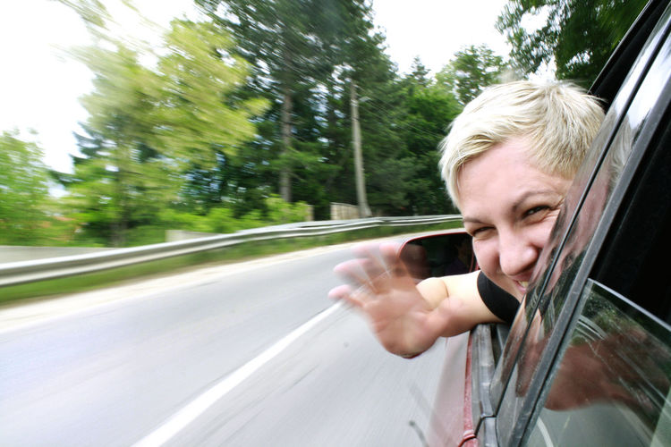Close-up portrait of cheerful woman looking through car window