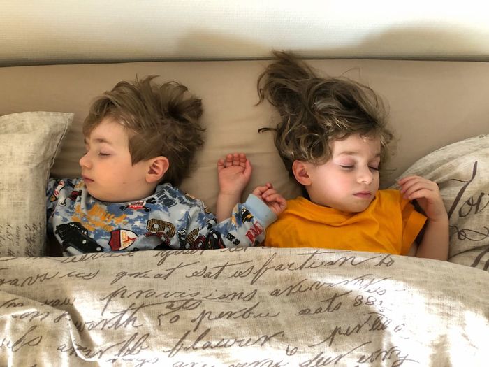 High angle view of siblings sleeping on bed at home