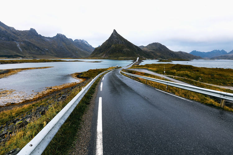 Empty road leading over the ocean with mountains in moskenesoya lofoten islands in norway