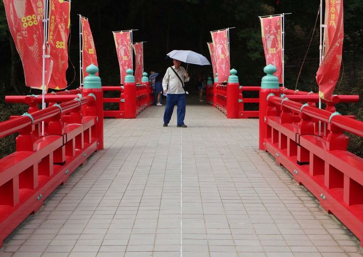 Full length of man standing on red umbrella