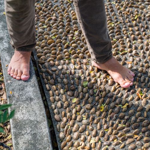 Low section of man standing on pebbles