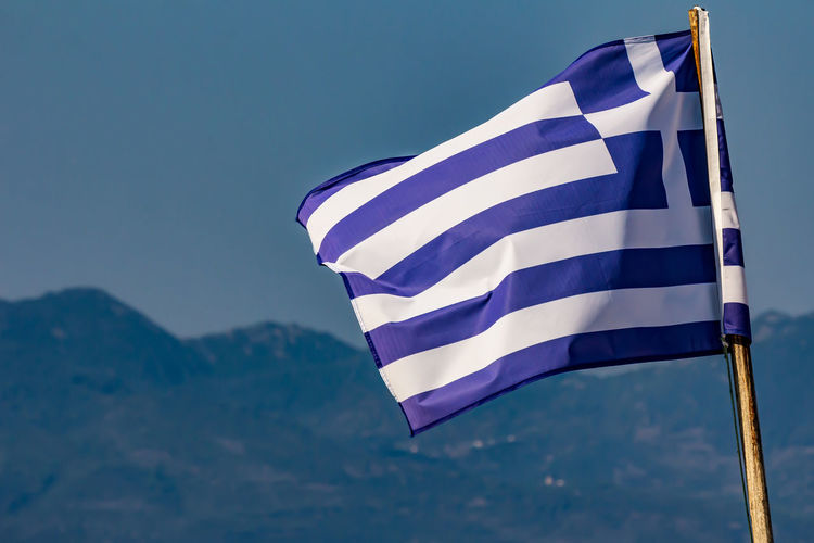 Greek national flag waving on blue sky background. hellenic republic, gr 