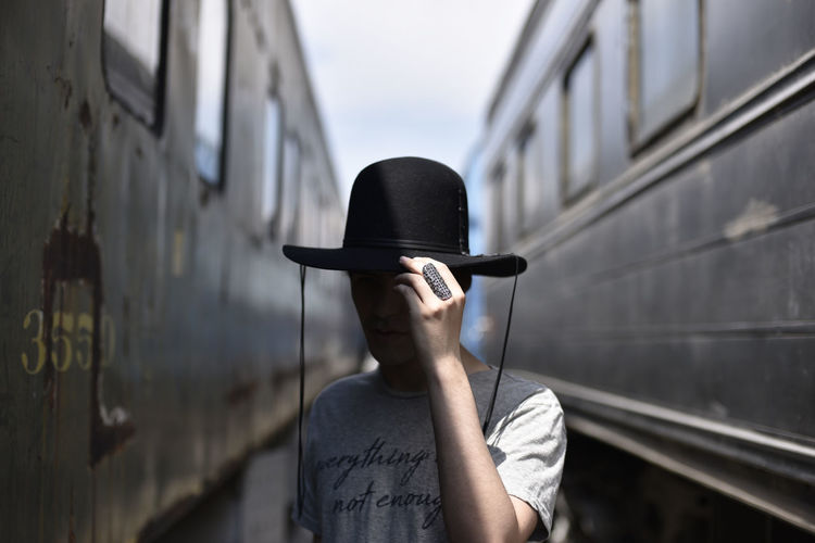 Man wearing hat against trains