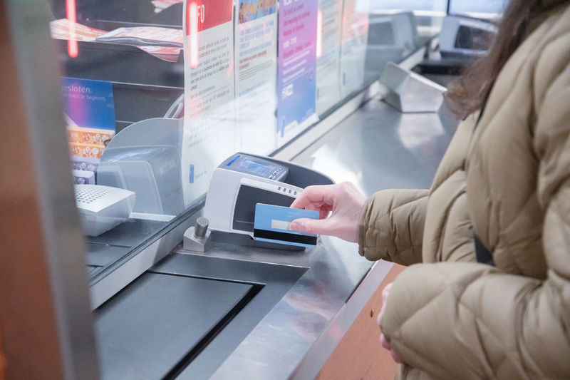 Young woman in a mask buys a subway ticket and pays with credit card contactless