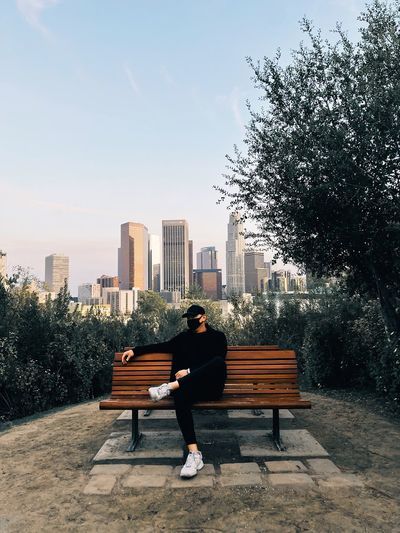 Man sitting on bench against city view in the back