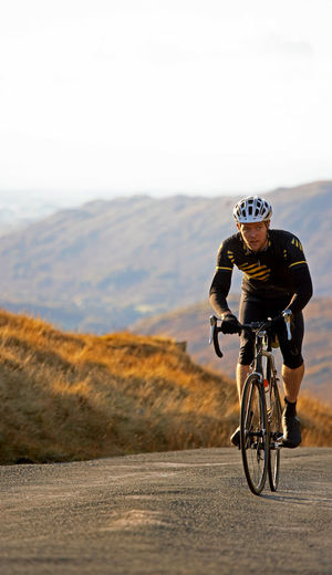 Cyclist approaching top of hill in the british lake district