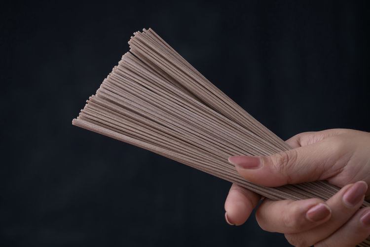 Cropped image of woman raw soba noodles against black background