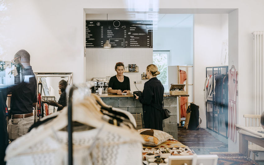 Senior owner talking to female customer in coffee shop