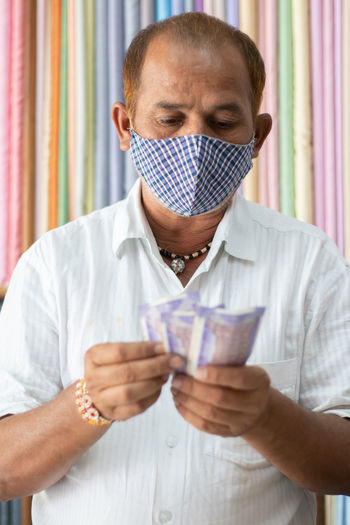 Portrait of man wearing mask and holding currency
