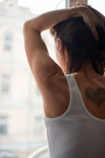 Rear view of woman with tattoo standing at home