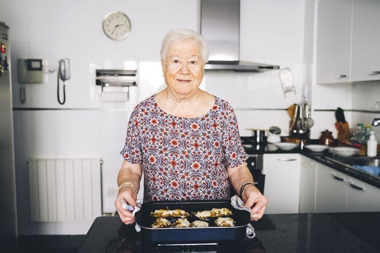 Portrait of senior woman with prepared food in the kitchen
