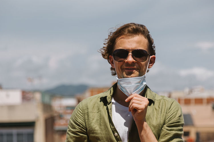 Young beautiful european man takes off protective medical mask from face. happy  positive guy  