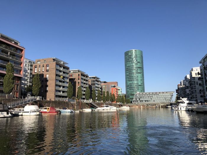River and buildings against clear blue sky