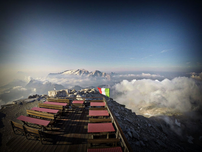 Italian flag by cafe on mountain against sky