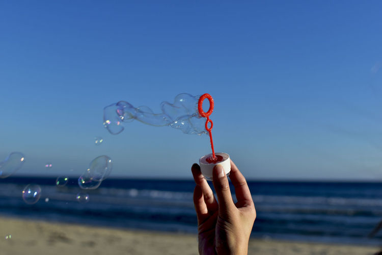 Hand holding bubble wand at beach