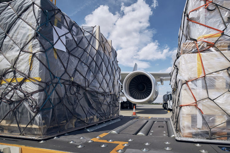 Preparation before flight. loading of cargo containers against jet engine of freight airplane.