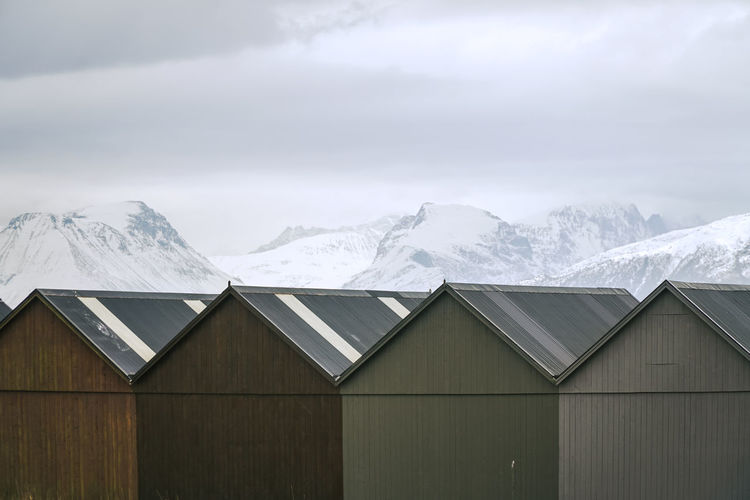 Triangle rooftops of boat houses and snowy mountains in the north of norway. classic scandinavia,