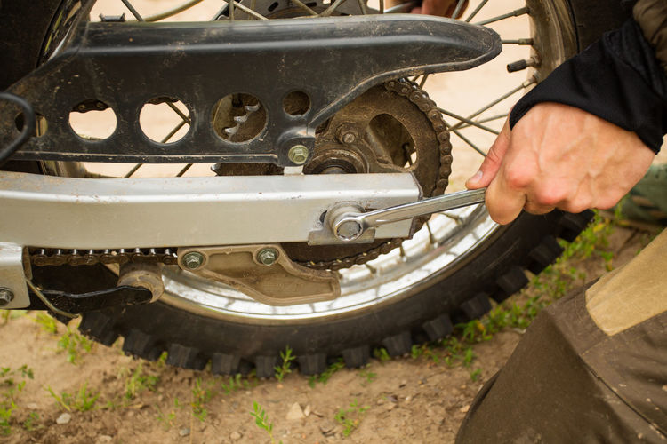 Close-up of man adjusting motorcycle tire with wrench