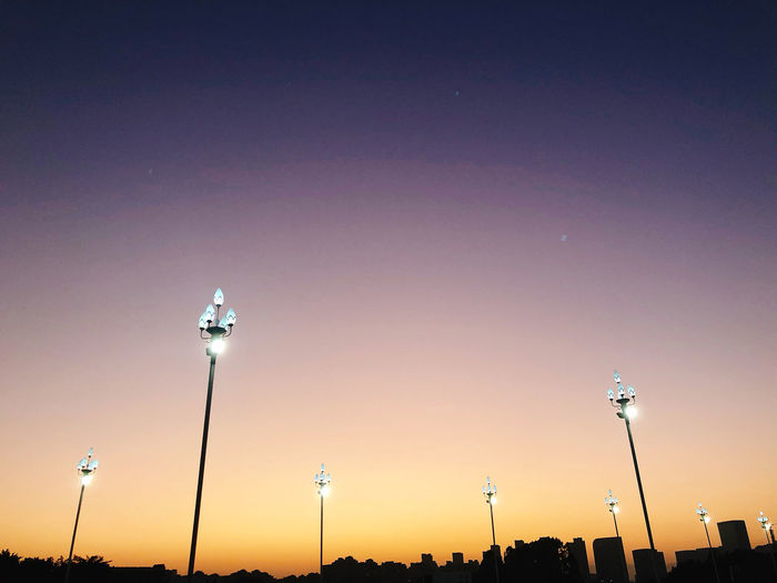 Low angle view of illuminated street lights against sky at night