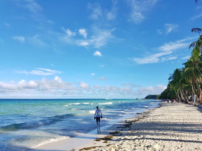 Man standing on beach against blue sky