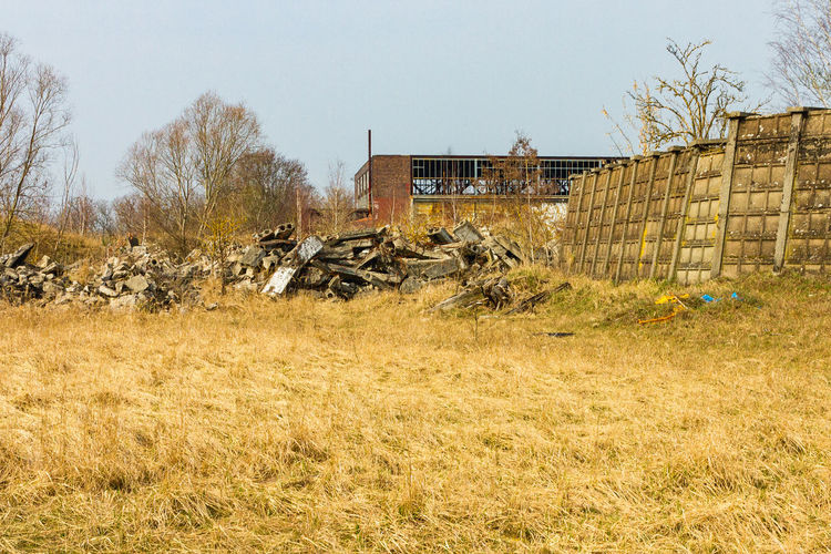 Abandoned building by trees on field against sky