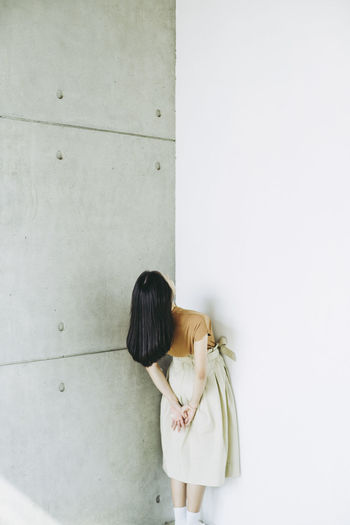 Woman bending against wall