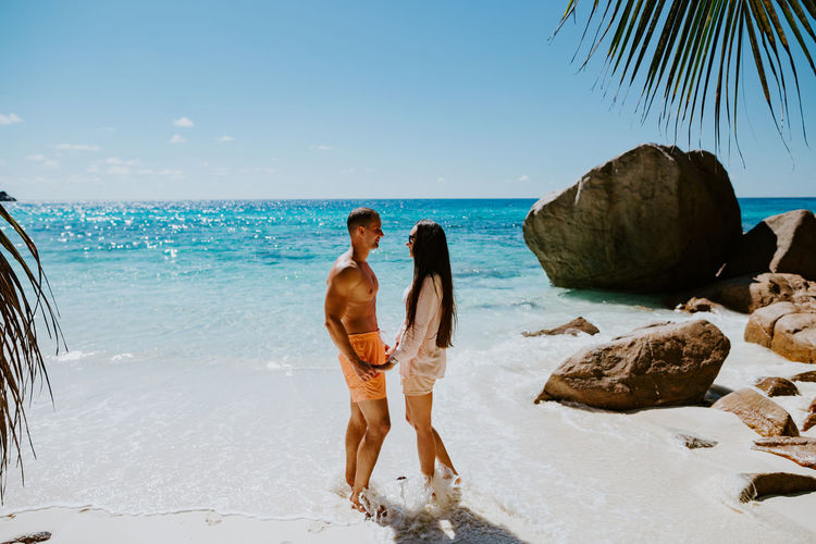 Side view of smiling couple standing at beach
