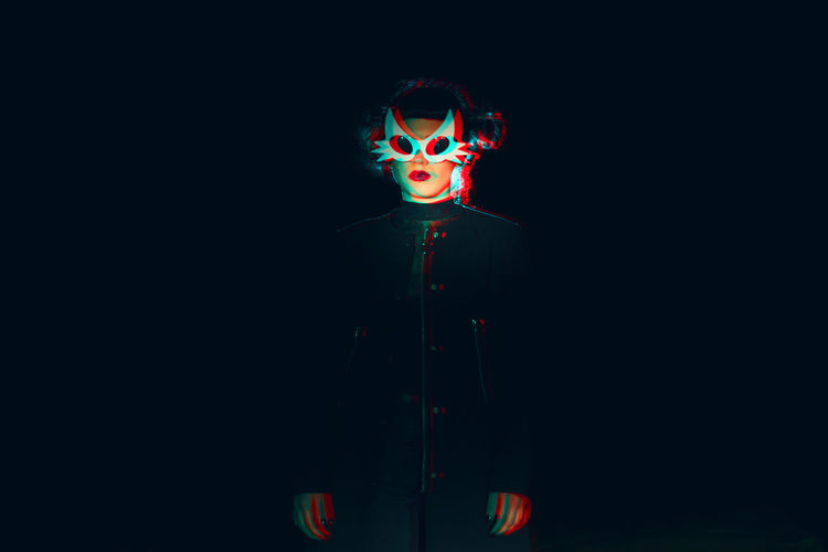 Woman wearing mask against black background