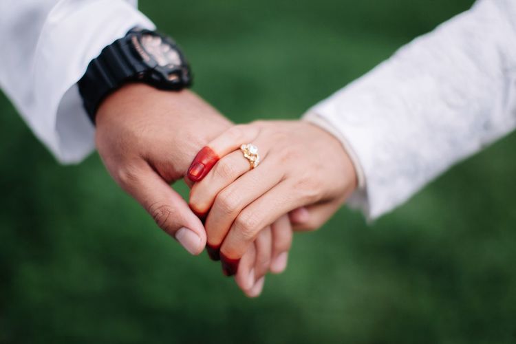 Cropped image of bride and groom holding hands