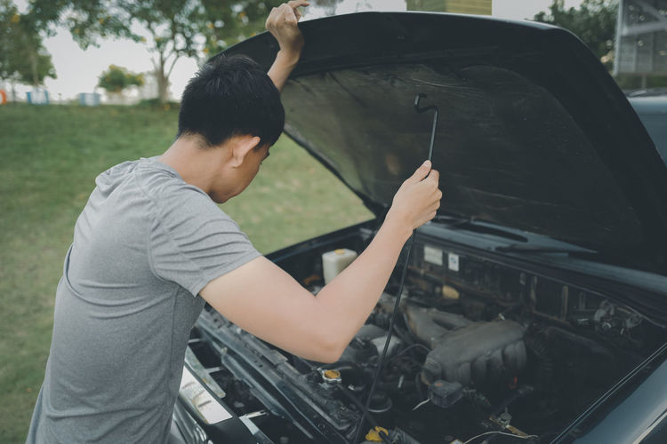 Young man driver checking a car engine ,opening front car hood