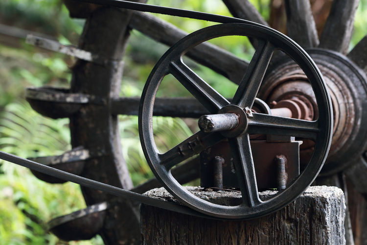 Close-up of old wheel against trees