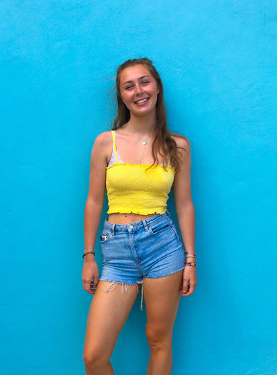 Portrait of a smiling young woman against blue wall