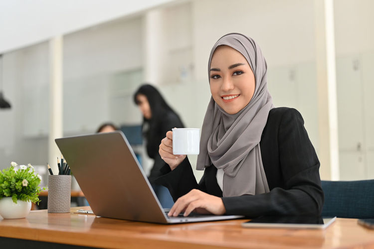 Young businesswoman using laptop while sitting on table