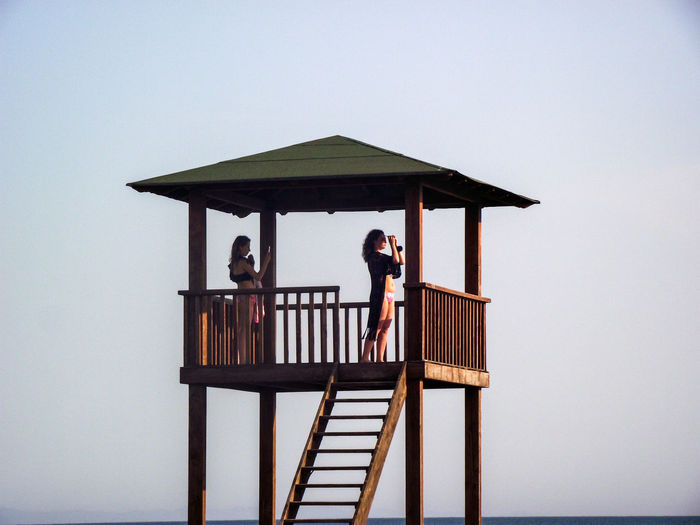 Women standing in lifeguard hut against sky