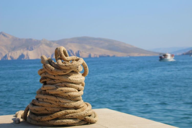 Stack of rope in sea against clear sky