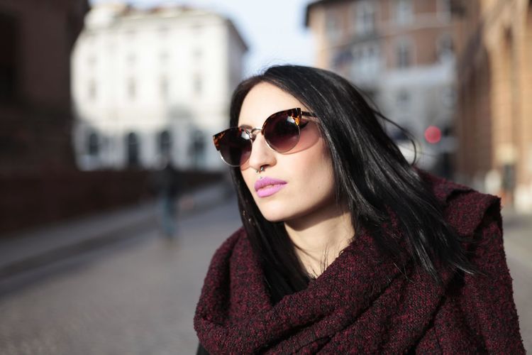 Fashionable young woman wearing sunglasses on street in city