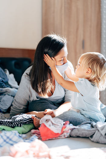 Mother wearing mask playing with daughter at home