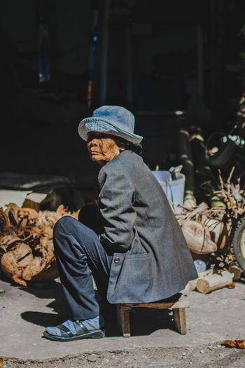 Side view of senior woman wearing hat sitting outdoors