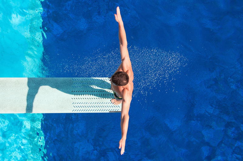 Directly above shot of man standing diving platform over pool