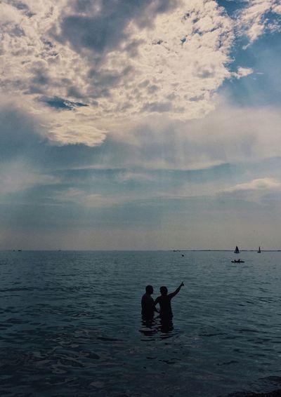 Silhouette people on sea against sky