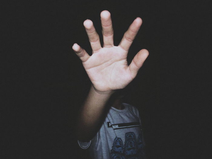 Boy gesturing while standing against black background