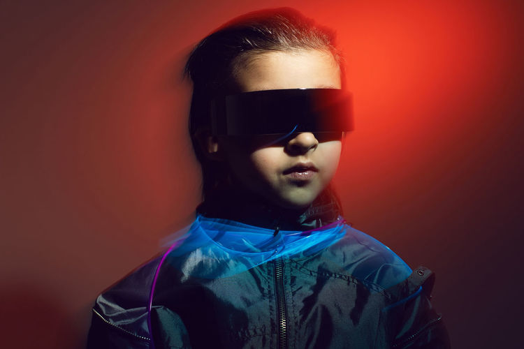 Portrait cyberpunk boy child in vr glasses in blue and red tones with wires. game, virtual reality