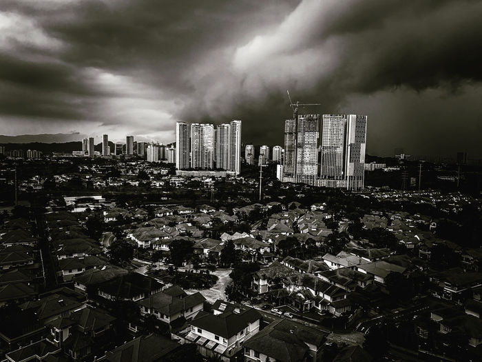 High angle view of modern buildings in city against storm clouds