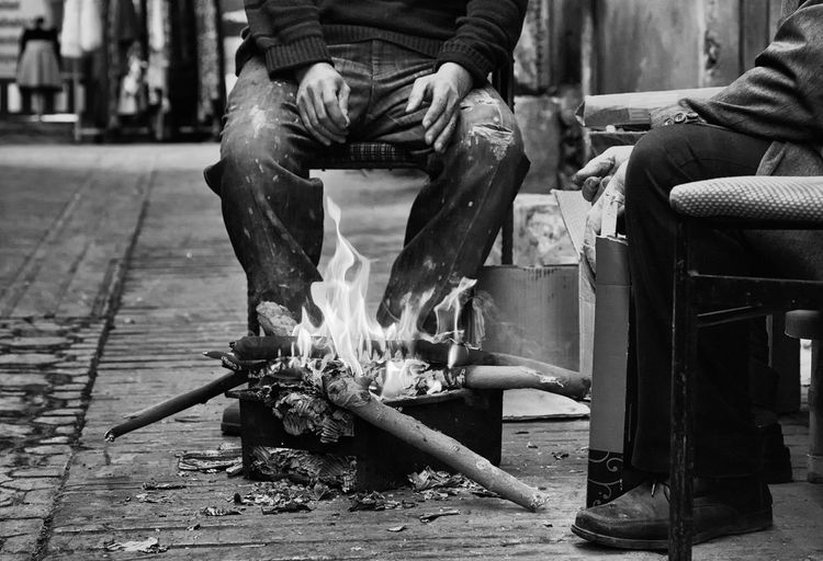 Man keeping warm by a fire 