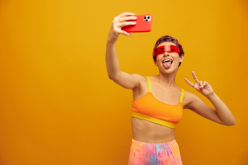 Portrait of young woman standing against yellow background